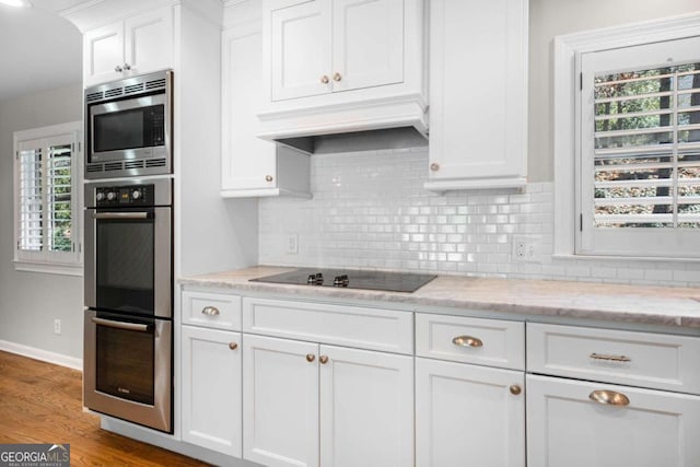 kitchen featuring light stone counters, stainless steel appliances, light wood-style floors, white cabinetry, and backsplash