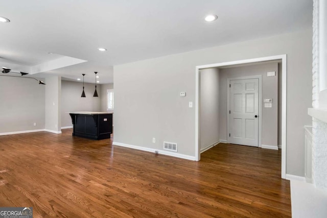 unfurnished living room featuring visible vents, baseboards, and dark wood finished floors