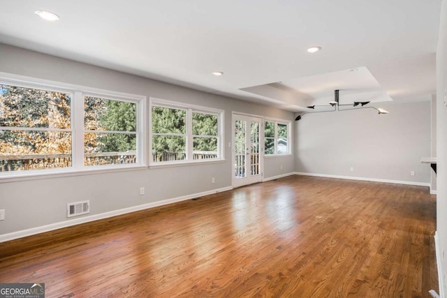 unfurnished living room featuring wood finished floors, visible vents, and baseboards