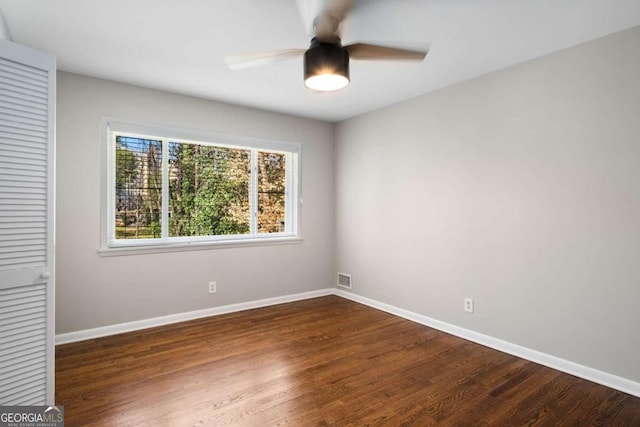 unfurnished room with dark wood-style floors, visible vents, and baseboards