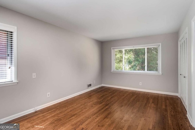 unfurnished bedroom with baseboards, multiple windows, and wood finished floors