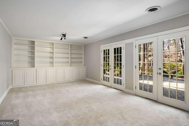 carpeted empty room featuring built in features, french doors, visible vents, and baseboards