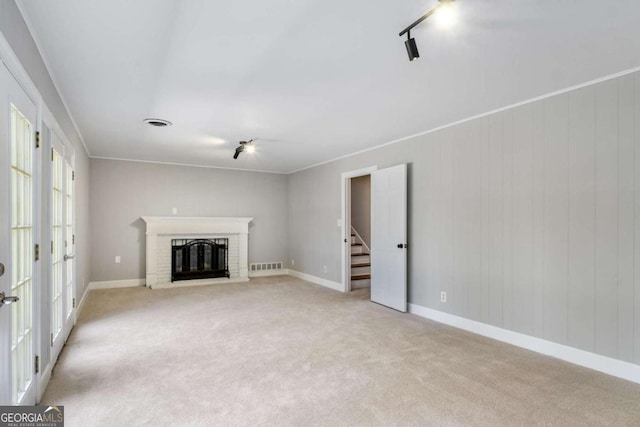 unfurnished living room featuring visible vents, light carpet, a fireplace, and stairs