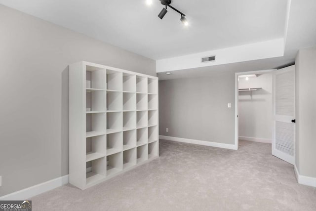 unfurnished bedroom with carpet, visible vents, baseboards, a closet, and a walk in closet