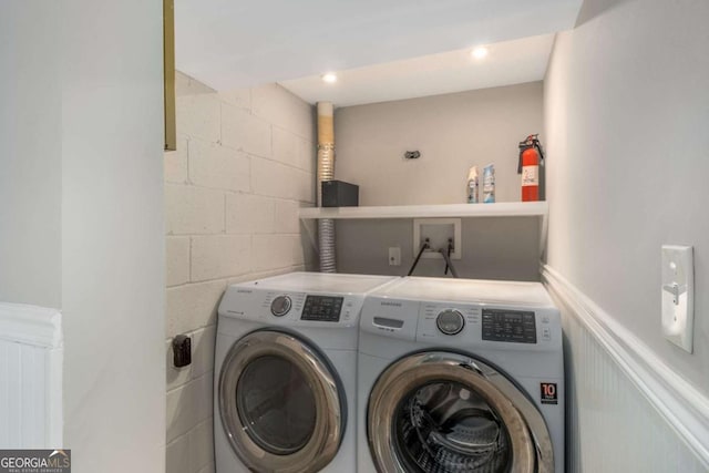 laundry room featuring concrete block wall, recessed lighting, a wainscoted wall, and washing machine and clothes dryer