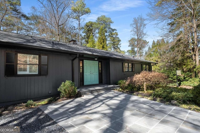 entrance to property with a shingled roof and a chimney