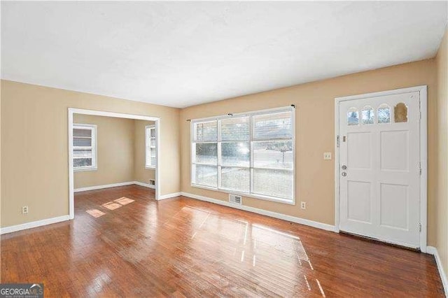 foyer entrance featuring visible vents, baseboards, and wood finished floors