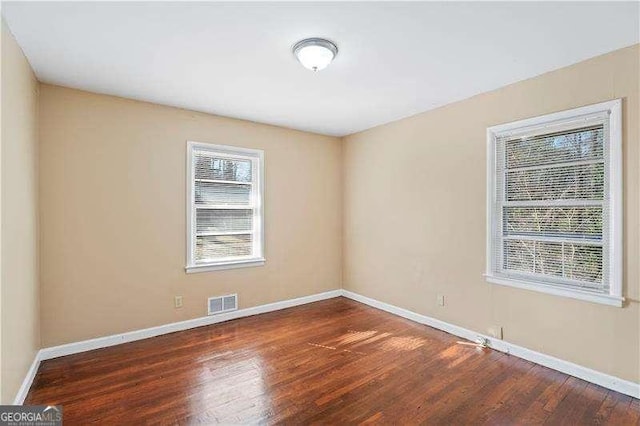 empty room featuring visible vents, baseboards, and wood finished floors