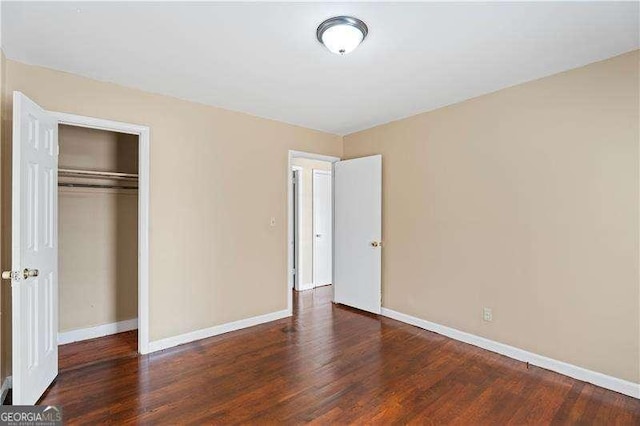 unfurnished bedroom featuring a closet, baseboards, and wood finished floors