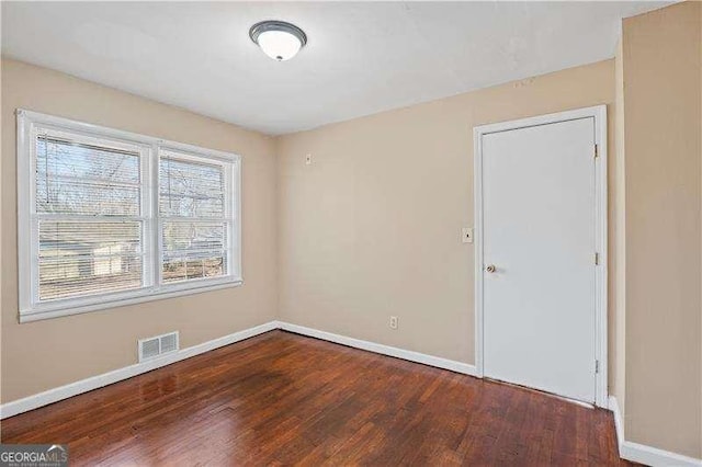 unfurnished room featuring wood finished floors, visible vents, and baseboards