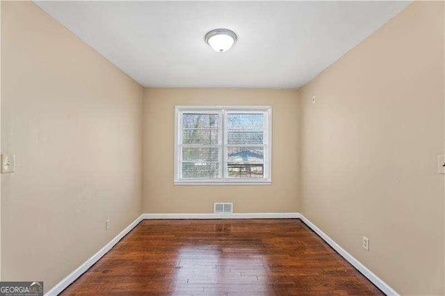 spare room with visible vents, baseboards, and wood finished floors