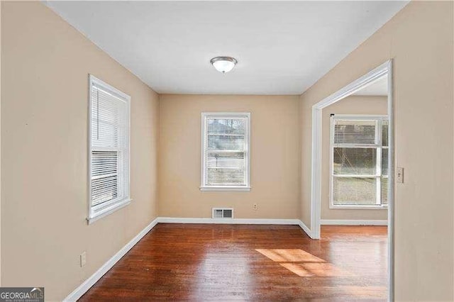 empty room featuring visible vents, baseboards, and wood finished floors