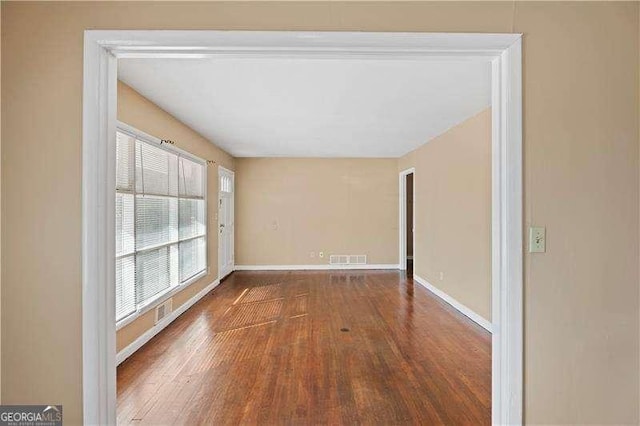 unfurnished room with wood finished floors, visible vents, and baseboards