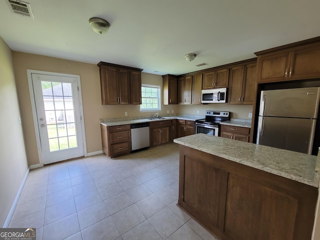 kitchen with baseboards, visible vents, light tile patterned flooring, a sink, and stainless steel appliances