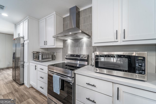 4159 Folks Dr, Blackshear, GA 31516 - kitchen featuring light countertops, wall chimney range hood, white cabinets, and appliances with stainless steel finishes