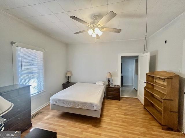 bedroom with visible vents, baseboards, light wood-type flooring, and a ceiling fan