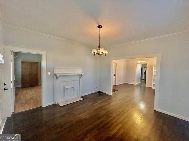 unfurnished living room with an inviting chandelier, wood finished floors, and baseboards