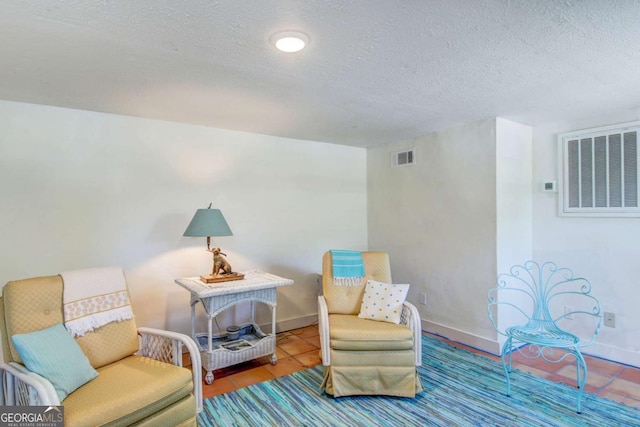 living area featuring visible vents, a textured ceiling, and baseboards