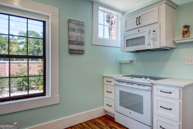 kitchen with plenty of natural light, white appliances, light countertops, and baseboards