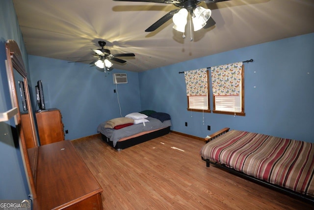 bedroom featuring a ceiling fan, wood finished floors, and a wall mounted AC