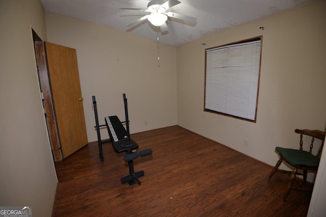 exercise area featuring a textured ceiling, wood finished floors, and a ceiling fan