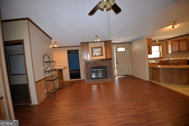 160 Cold Branch Rd, Eatonton, GA 31024 - unfurnished living room with dark wood-type flooring, a textured ceiling, a brick fireplace, and a ceiling fan