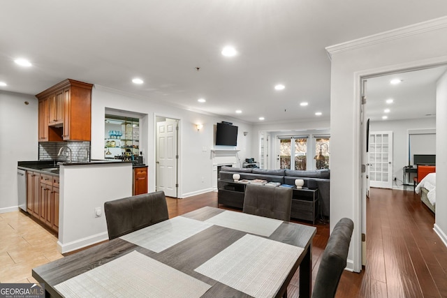 dining space with baseboards, light wood-style flooring, a fireplace, recessed lighting, and ornamental molding