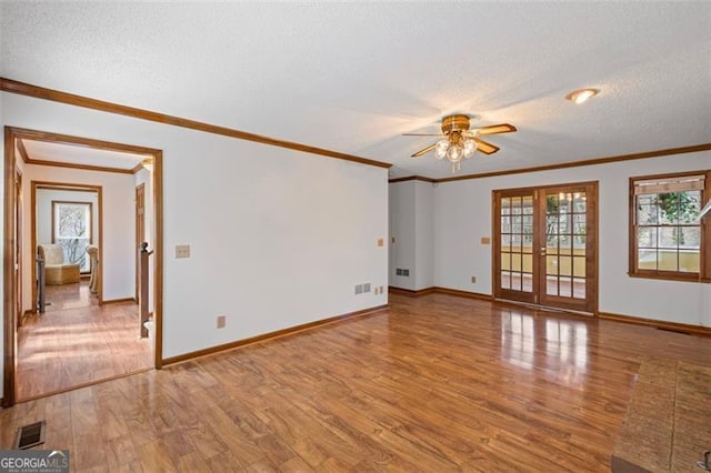 unfurnished room featuring french doors, visible vents, light wood finished floors, and a textured ceiling