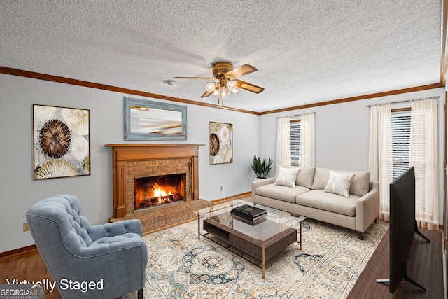 living room featuring a fireplace, a textured ceiling, crown molding, and wood finished floors