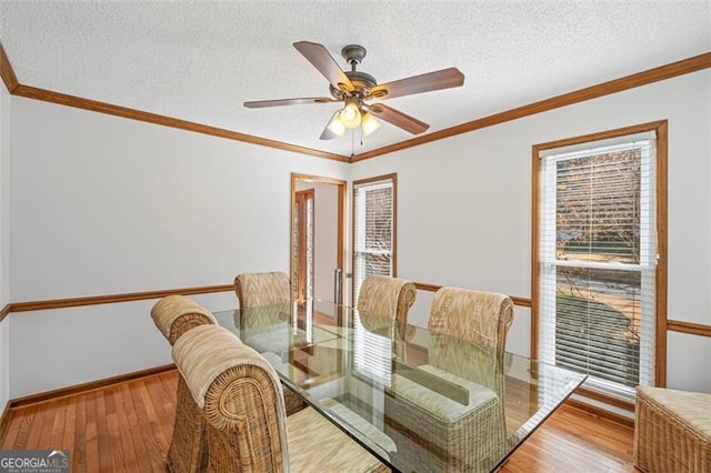 dining room with wood-type flooring, a textured ceiling, and ornamental molding