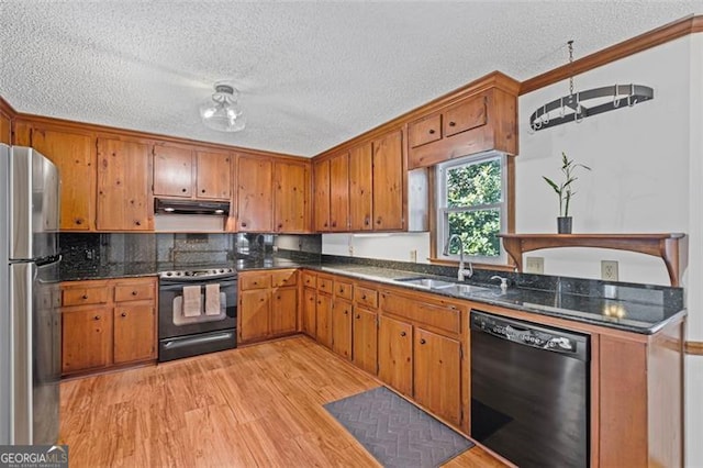 kitchen featuring under cabinet range hood, black appliances, brown cabinetry, and a sink