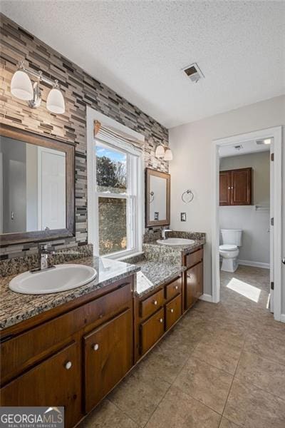 bathroom with a textured ceiling, visible vents, and a sink