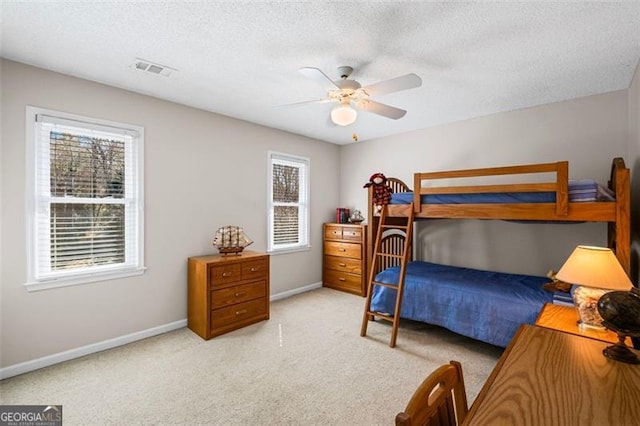 carpeted bedroom featuring visible vents, a textured ceiling, baseboards, and a ceiling fan