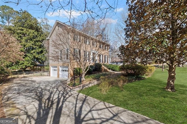 colonial house featuring a front yard, an attached garage, fence, and aphalt driveway