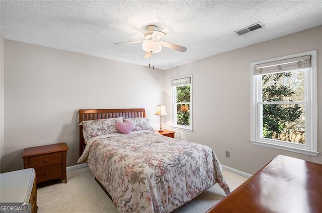 bedroom featuring visible vents, light colored carpet, a textured ceiling, and baseboards