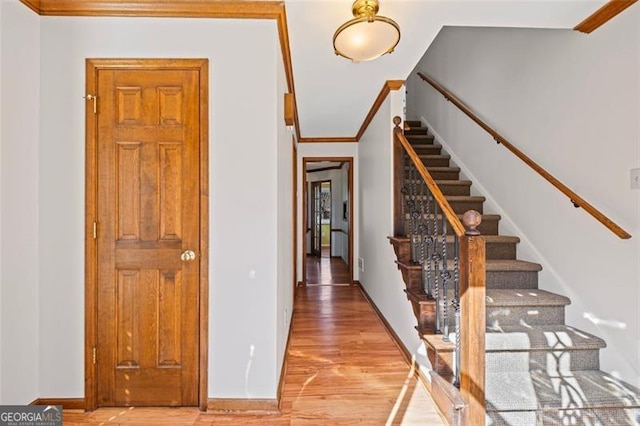 staircase featuring baseboards, wood finished floors, and crown molding