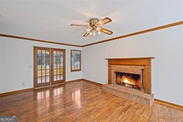 unfurnished living room featuring a brick fireplace, french doors, crown molding, and wood finished floors