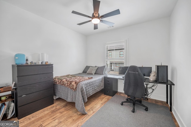 bedroom with light wood finished floors, visible vents, a ceiling fan, and baseboards