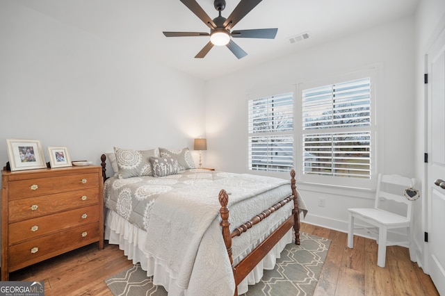 bedroom with wood finished floors, visible vents, and ceiling fan