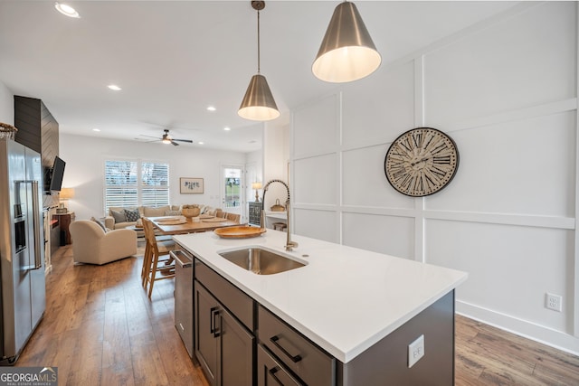 kitchen with a sink, appliances with stainless steel finishes, wood finished floors, and a decorative wall