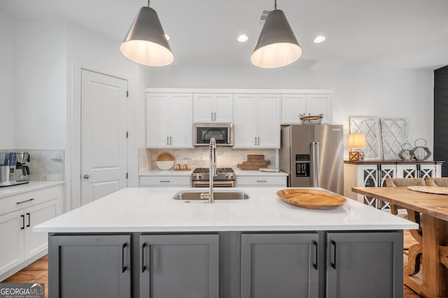 kitchen with tasteful backsplash, white cabinets, appliances with stainless steel finishes, and gray cabinetry