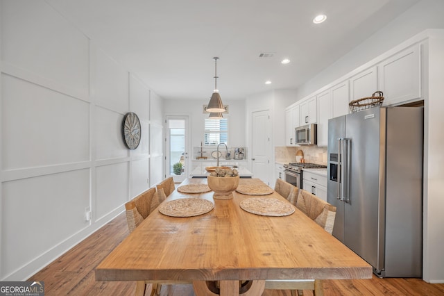 dining area featuring a decorative wall, recessed lighting, visible vents, and wood finished floors