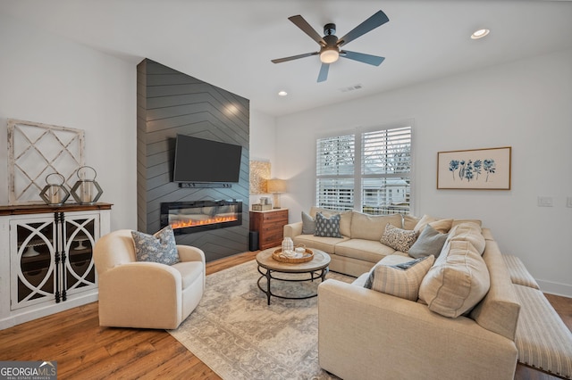 living room with wood finished floors, recessed lighting, a fireplace, and visible vents