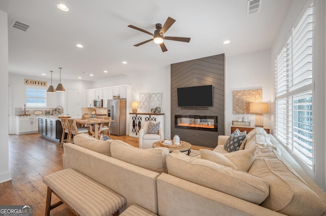 living room featuring recessed lighting, light wood-style floors, visible vents, and a large fireplace