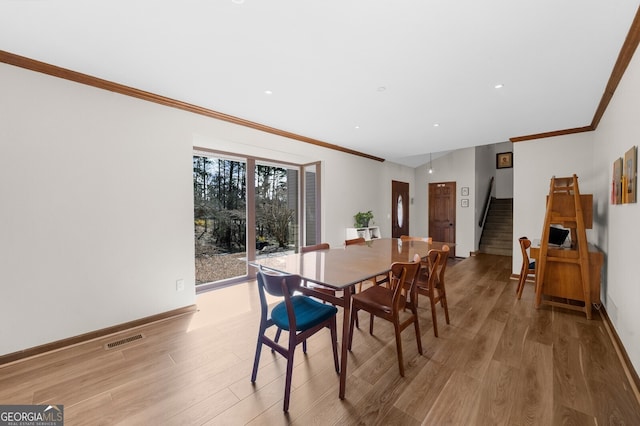 dining area with visible vents, crown molding, baseboards, stairs, and light wood-style flooring