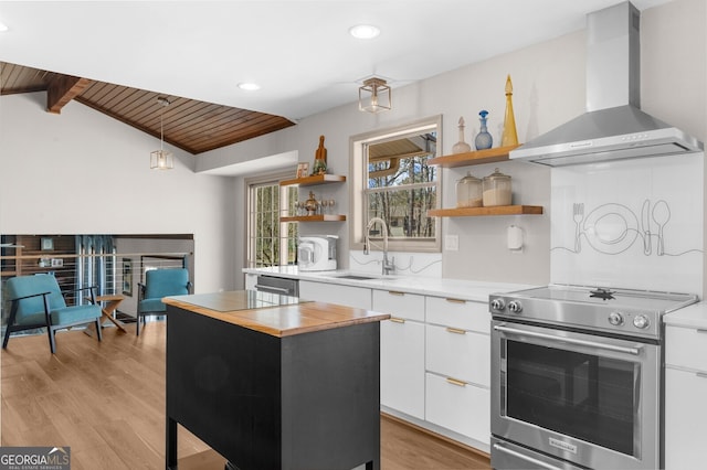 kitchen with butcher block countertops, open shelves, a sink, stainless steel electric stove, and wall chimney range hood