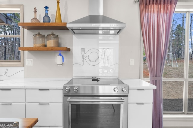 kitchen featuring light stone countertops, open shelves, electric stove, white cabinetry, and wall chimney range hood