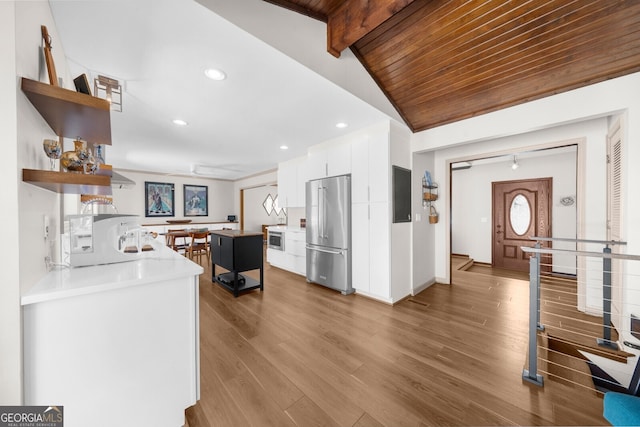 kitchen with lofted ceiling with beams, high quality fridge, wood finished floors, white cabinetry, and open shelves