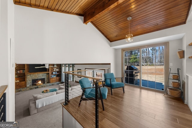 sitting room featuring wood finished floors, high vaulted ceiling, a fireplace, wooden ceiling, and beamed ceiling