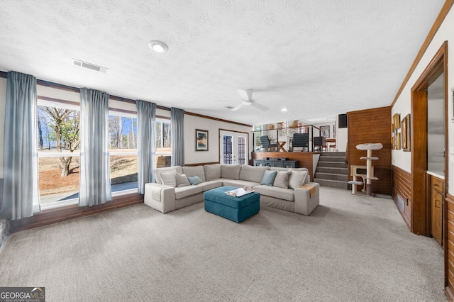 carpeted living room with visible vents, stairway, a textured ceiling, and ceiling fan